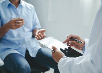 A healthcare provider having a conversation with a patient to review the patient's chart and their health circumstances.