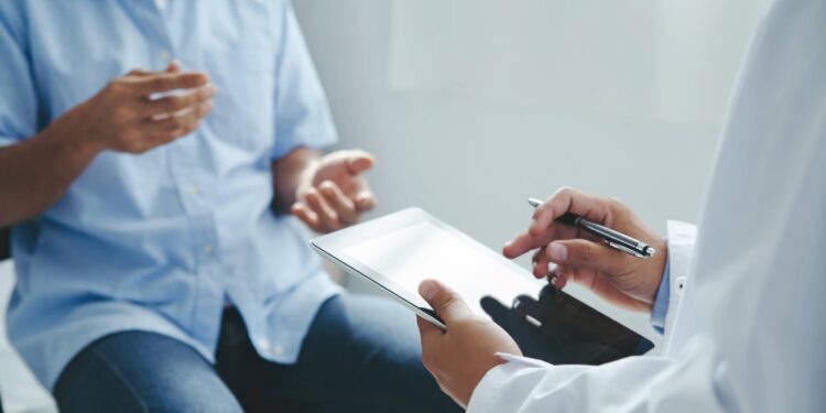 A healthcare provider having a conversation with a patient to review the patient's chart and their health circumstances.