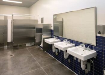A modern, well-lit, and freshly sterilized commercial men's restroom, located somewhere in a medical facility.