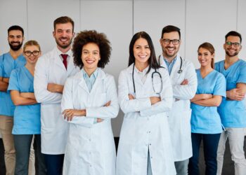 A group of doctors and nurses standing together. They all have their arms crossed and look happy to help.
