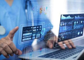 A doctor is using cloud technology and online storage for data backup. They're wearing blue scrubs and a stethoscope.