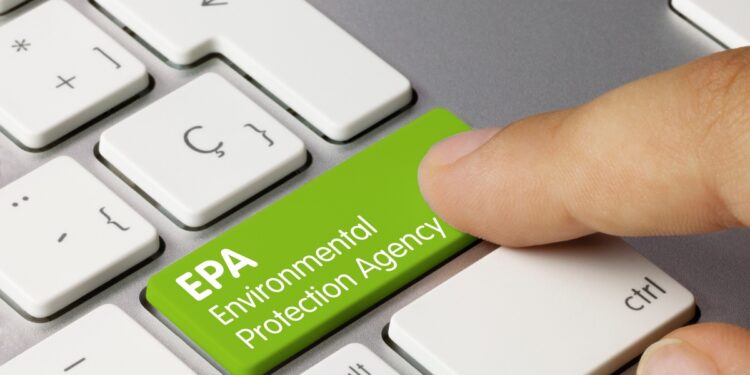 A person hits a bright green button on a computer keyboard that reads 'EPA Environmental Protection Agency'