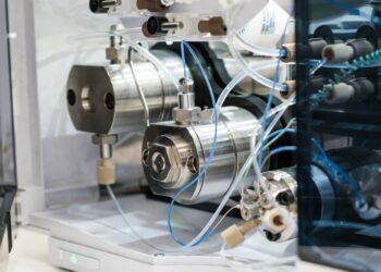 A close-up of analytical laboratory equipment with stainless-steel components, tubing, and fittings inside machine.
