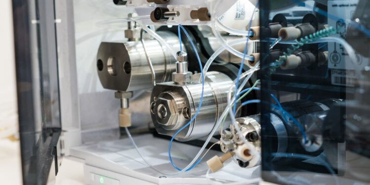 A close-up of analytical laboratory equipment with stainless-steel components, tubing, and fittings inside machine.