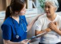 A mature patient expressing a concern about chest pain to a doctor in scrubs, who is patiently listening to their worries.
