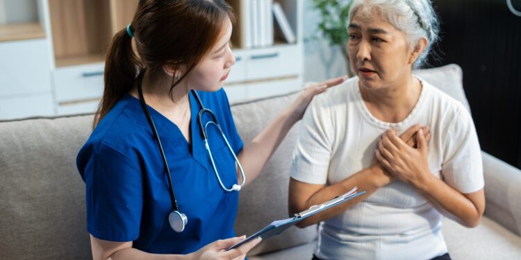 A mature patient expressing a concern about chest pain to a doctor in scrubs, who is patiently listening to their worries.
